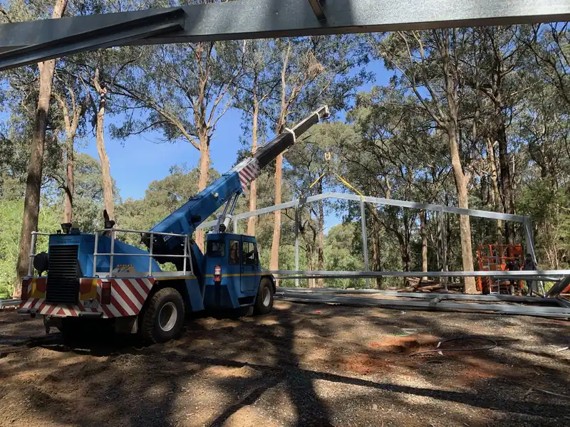 Blue crane working under a steel frame on a bush building site